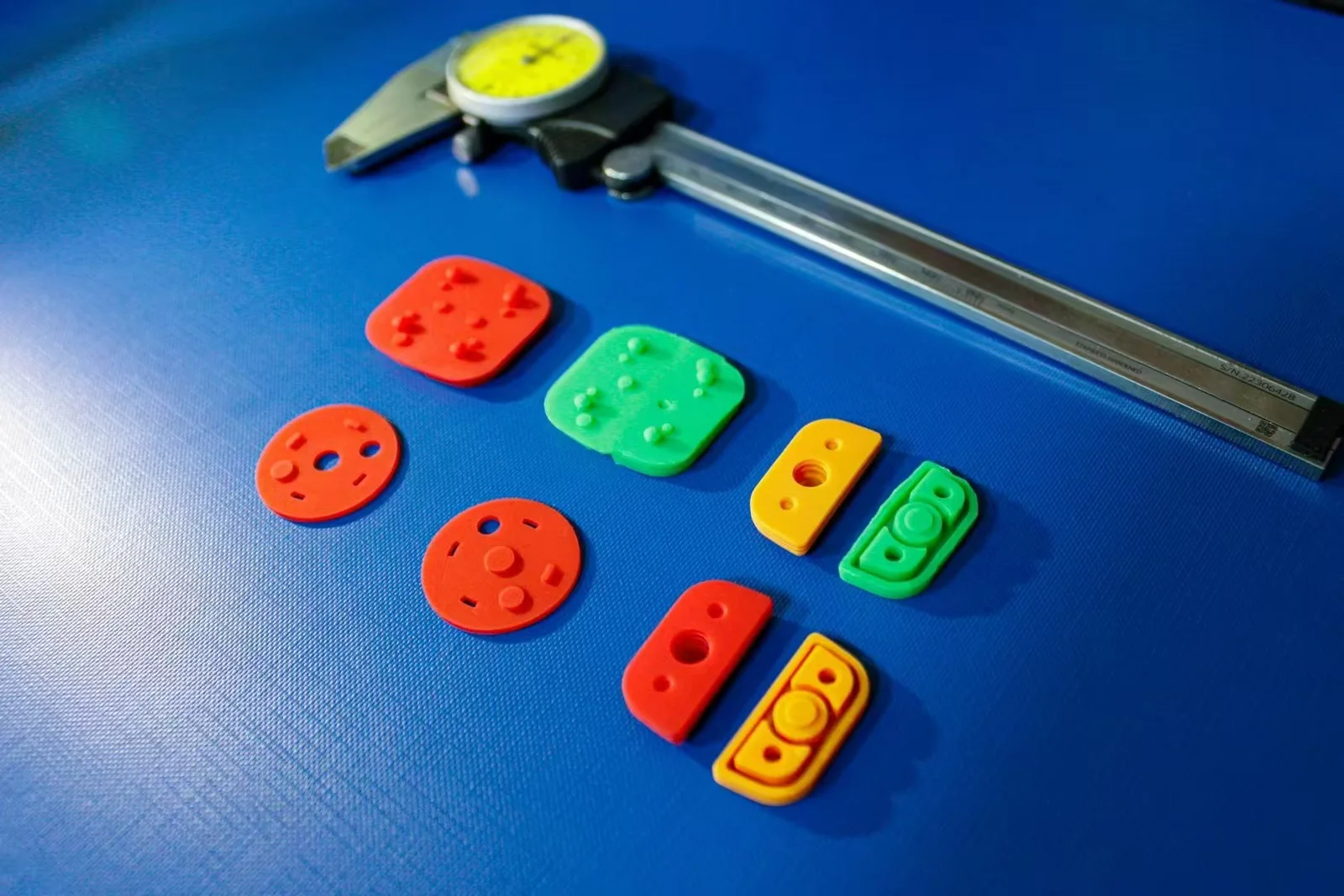 Colored silicone sample parts for an electronic atomizer project beside a caliper